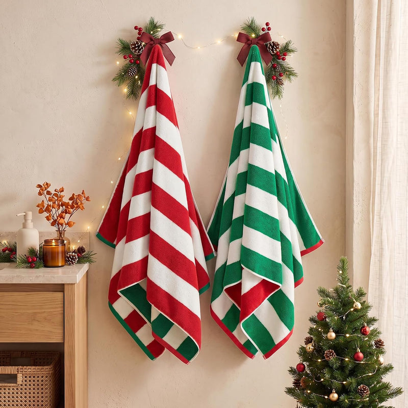 REDKISS red and green striped Christmas bath towels hanging in a cozy holiday bathroom decorated with festive greenery, warm lights and a Christmas tree. #color_christmas